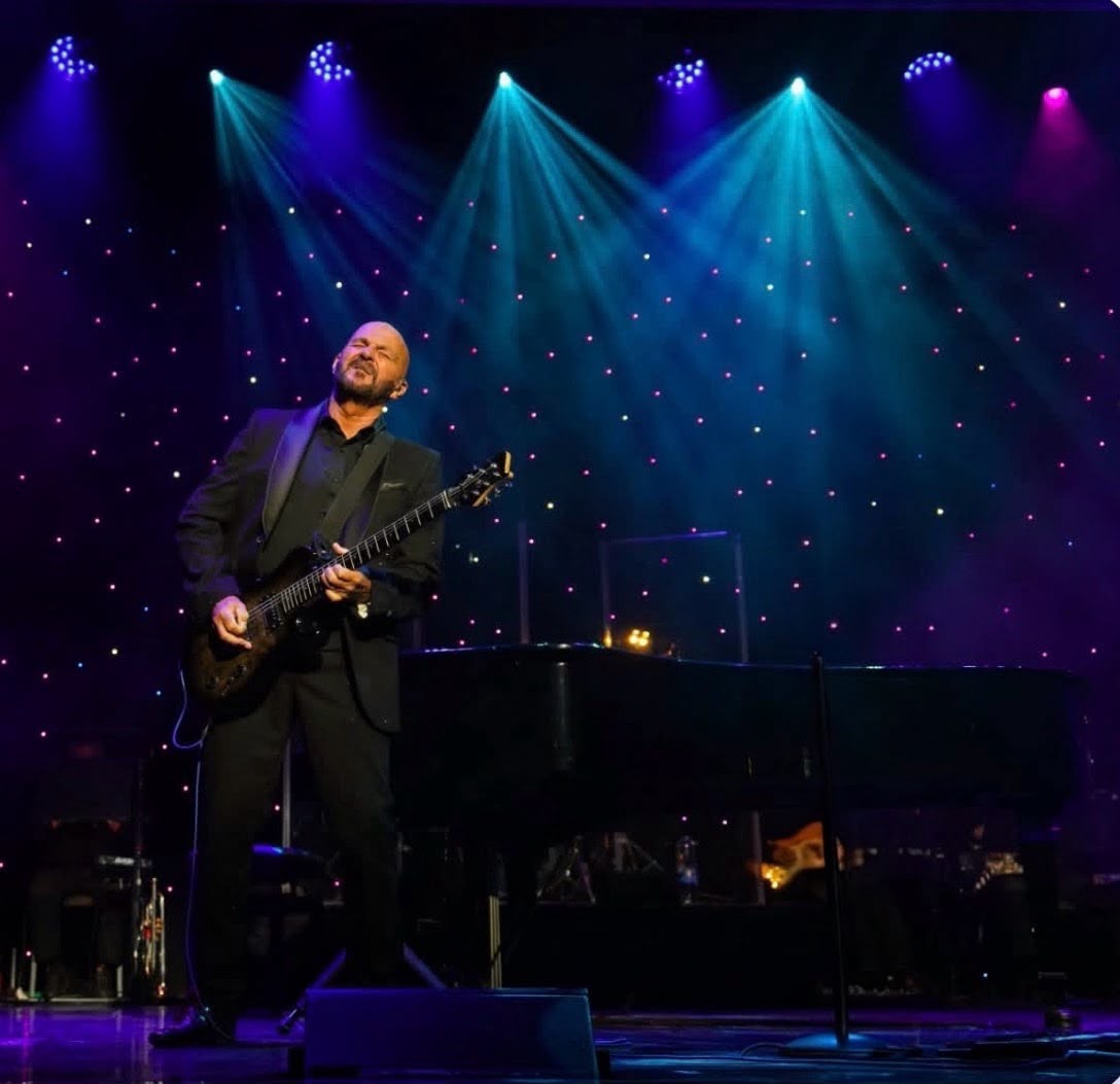 Shaun Perry playing a guitar solo beneath blue stage lights