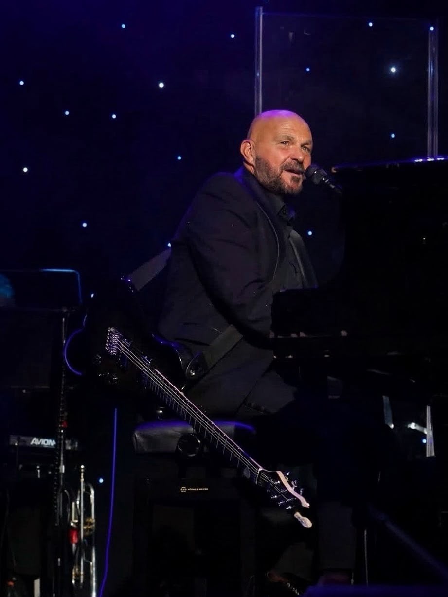 Shaun Perry singing while playing a grand piano on stage