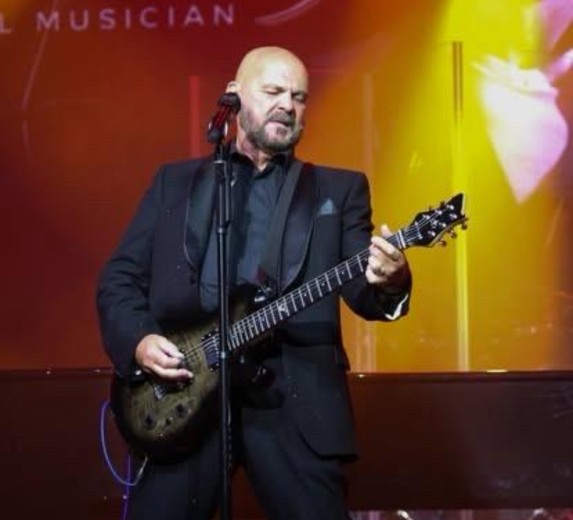 Shaun Perry singing and playing guitar during his live show