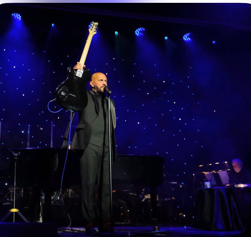 Shaun Perry raising his guitar during a live stage performance